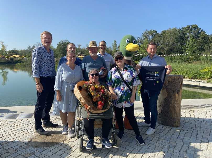 Irene Popp (vorn in der Mitte) bekam als 400.000ste Besucherin von Kirchheims Erstem Bürgermeister Stephan Keck (links) sowie den Geschäftsführern der Kirchheim 2024 GmbH, Johannes Pinzel (Dritter von rechts) und Maximilian Heyland (rechts), Gartenschau-Gin, Gartenschau-Stofftasche und einen Blumenstrauß überreicht. | Foto: Landesgartenschau Kirchheim/Schreib