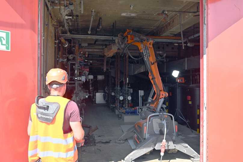Der ferngesteuerte Ein-Tonnen-Abrissroboter DXR 145 von Husqvarna holt die Metallrohre im Heizungsraum von der Decke und zerkleinert sie für den Abtransport. | Foto: QUATEX Der ferngesteuerte Ein-Tonnen-Abrissroboter DXR 145 von Husqvarna holt die Metallrohre im Heizungsraum von der Decke und zerkleinert sie für den Abtransport. | Foto: QUATEX
