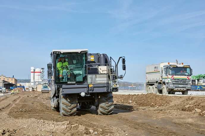 Nach dem Recycling kommt die Bodenstabilisierung: Der Wirtgen WRC 240i (links) bricht und durchmischt das Bodenmaterial 50 cm tief, der Streumaster SW 16 MC (rechts) bringt das Zementgemisch auf. | Foto: Wirtgen Group