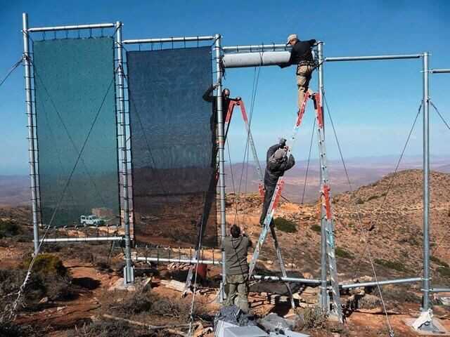 Aus Stahlpfosten und Rohren wird der Nebelkollektor auf dem berg zusammengebaut. Die Nebelsammelnetze werden nach dem Aufbau der Stahlkonstruktion eingesetzt.