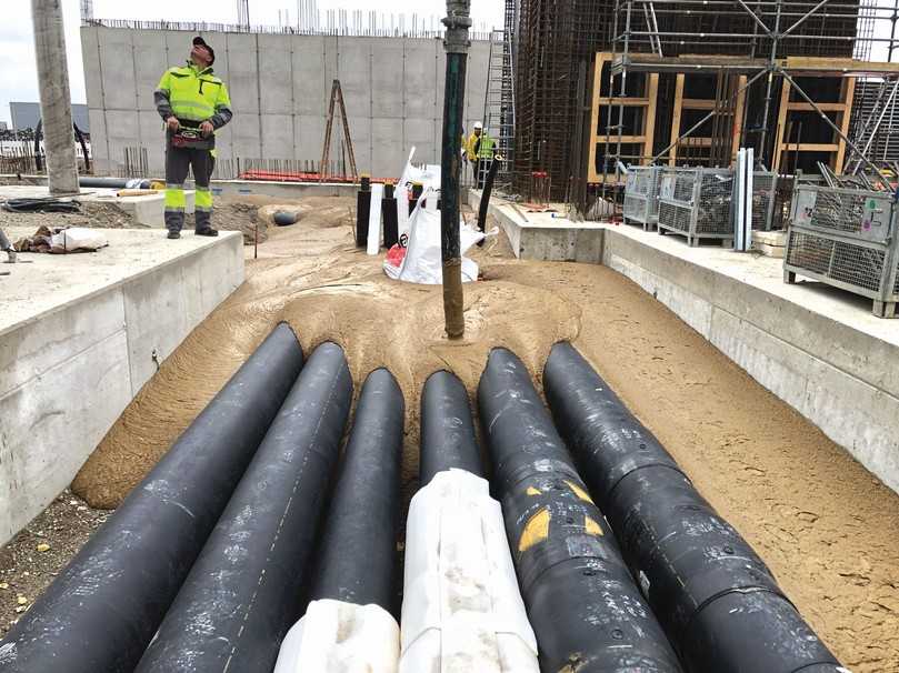 Einbau einer neuen Fernwärmeleitung durch die TBG Rott GmbH aus Kelheim auf der Baustelle des LabCampus am Flughafen München-Erding. Bei der Ausschreibung hatte der Rohrhersteller speziell darauf bestanden, dass er nur dann in die Gewährleistung gehen wird, wenn seine Fernwärmerohre in – nach RAL-Gütezeichen 507 zertifizierten – Flüssigboden eingebettet werden. | Foto: TBG Rott GmbH