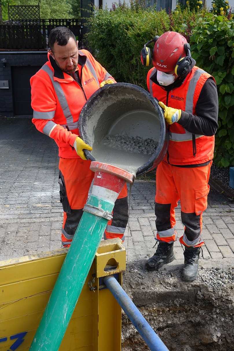 Thomas Sy (re.) und Tom Textor von der Betriebskolonne der Gemeindewerke Burbach beim Einbringen des fließfähigen Ombran MC FG plus-Vergussmörtels über ein Kunststoffrohr | Foto: Preco Thomas Sy (re.) und Tom Textor von der Betriebskolonne der Gemeindewerke Burbach beim Einbringen des fließfähigen Ombran MC FG plus-Vergussmörtels über ein Kunststoffrohr | Foto: Preco