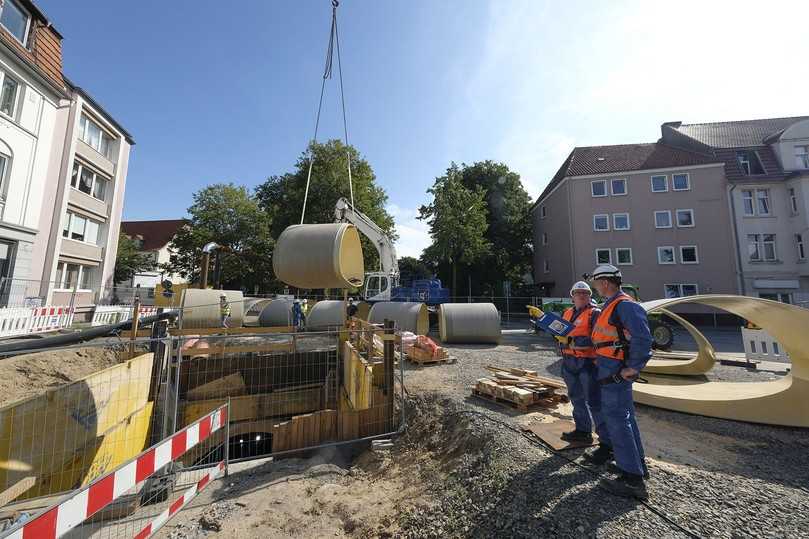 Die GFK-Rohre werden mit einem Kran in die Baugrube abgelassen und von dort mit einem speziellen Fahrwagen in die Lutter-Verrohrung eingefahren. Alexander Garen (Umweltbetrieb der Stadt Bielefeld, rechts) und Prüfingenieur Guido Heidbrink (Güteschutz Kanalbau, links) besprechen den Sanierungsfortschritt. | Foto: Güteschutz Kanalbau