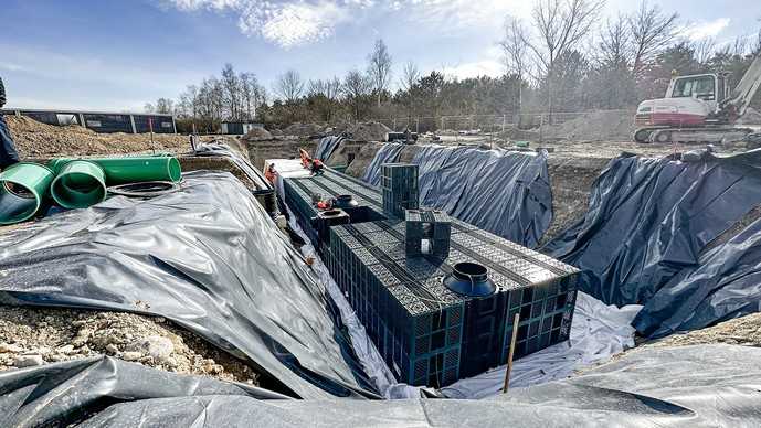 Wegen der Bodenkontaminierung auf dem ehemaligen Militärgelände wurde die Baugrube während der Montage der Rigolen-Blöcke mit Folien abgesichert. | Foto: Fränkische
