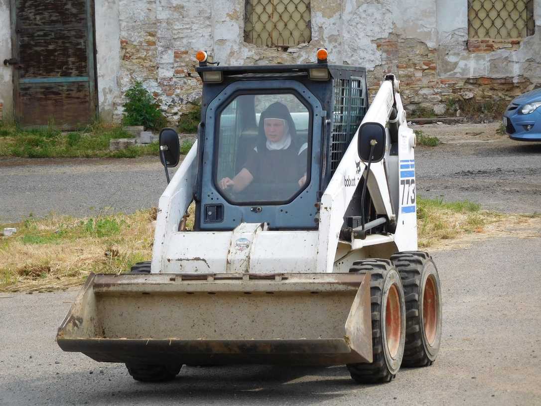 Nonnen fahren mit Bobcat-Lader im Kloster