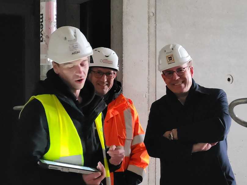 Jörg Osmers (m.), Leiter Bauen im Bestand bei der Alfed Döpker Bauunternehmung, und Jörn P. Makko (r.), Hauptgeschäftsführer Bauindustrieverband Niedersachsen-Bremen, lassen sich die Funktionen des Bauroboters erklären. | Foto: B_I/bb