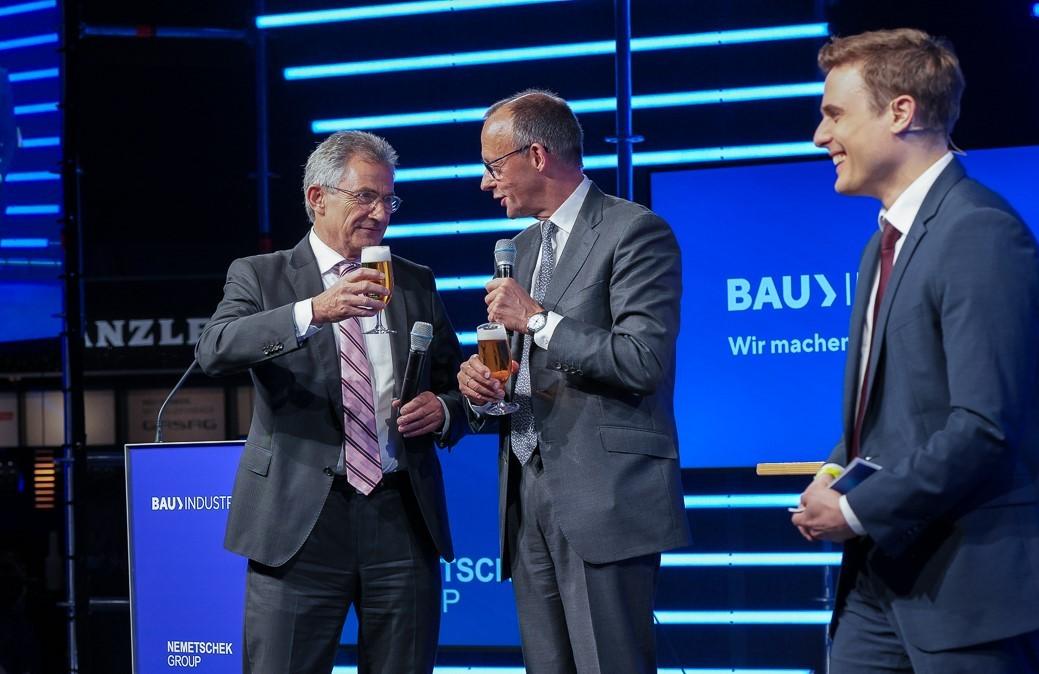 Ein Bierchen mit Friedrich Merz (Mitte): Bauindustrie-Präsident Peter Hübner auf dem Podium am Tag der Bauindustrie 2024, rechts Moderator Constantin Schreiber. | Foto: HDB/Maren Strehlau/O. Walterscheid