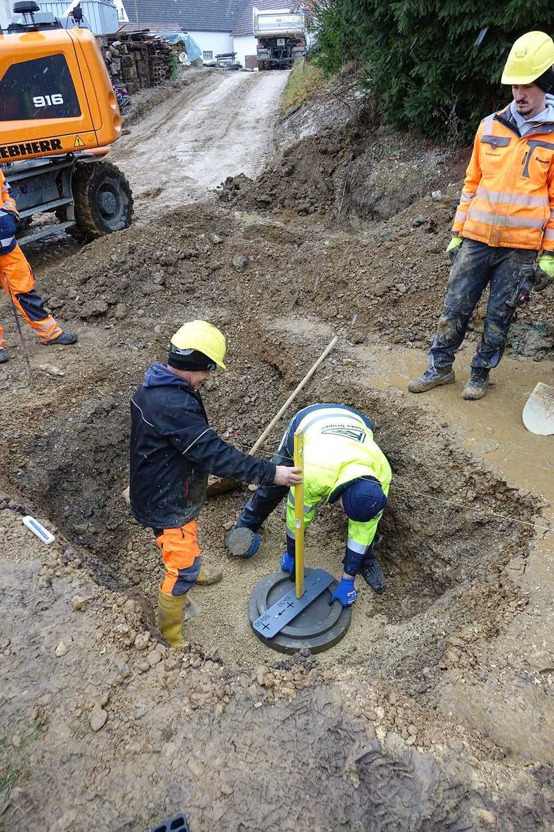 Die Grundplatte des Funke-Ablaufs wird gelegt, wobei die Ausrichtung zum Bordstein mittels Wasserwaage und Positionsscheibe wichtig ist. | Foto: Funke Kunststoffe